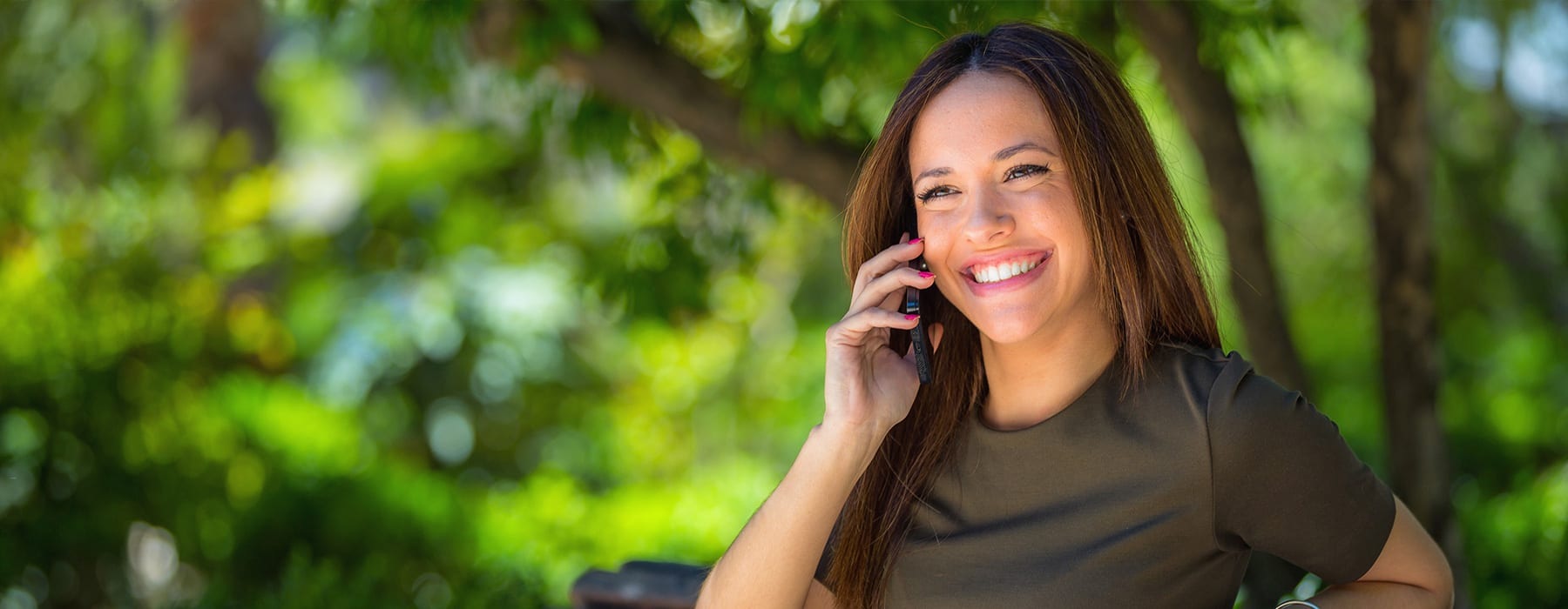 lifestyle image of a woman smiling while on the phone outdoors